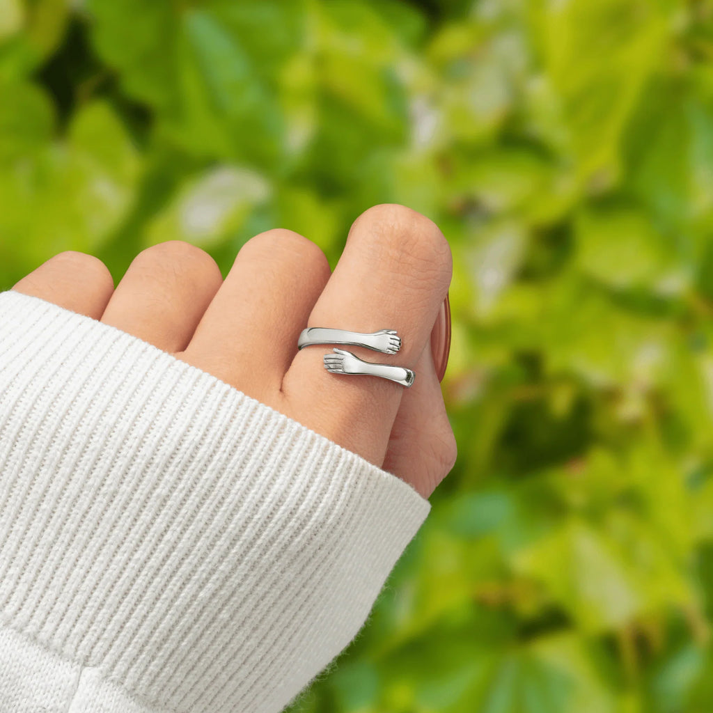 Anillo abrazo de acero puesto en el dedo, con las dos manos rodeando el aro
