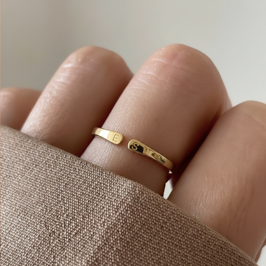Anillo dorado con dos iniciales puesto en el dedo