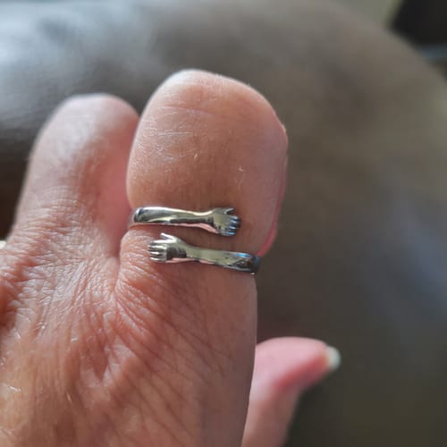 Detalle del anillo abrazo en el dedo: los dos brazos que se cierran alrededor