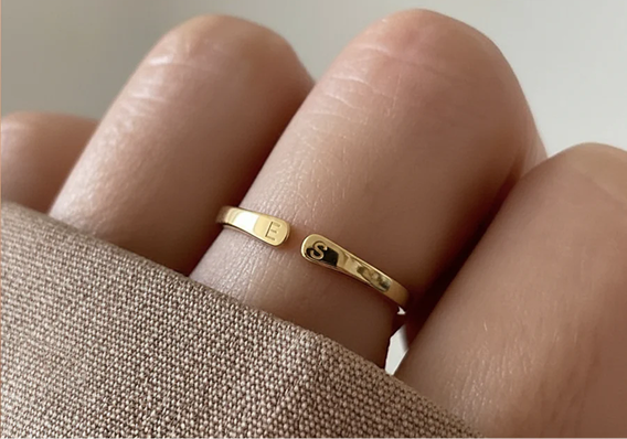 Anillo dorado con dos iniciales grabadas, puesto en la mano