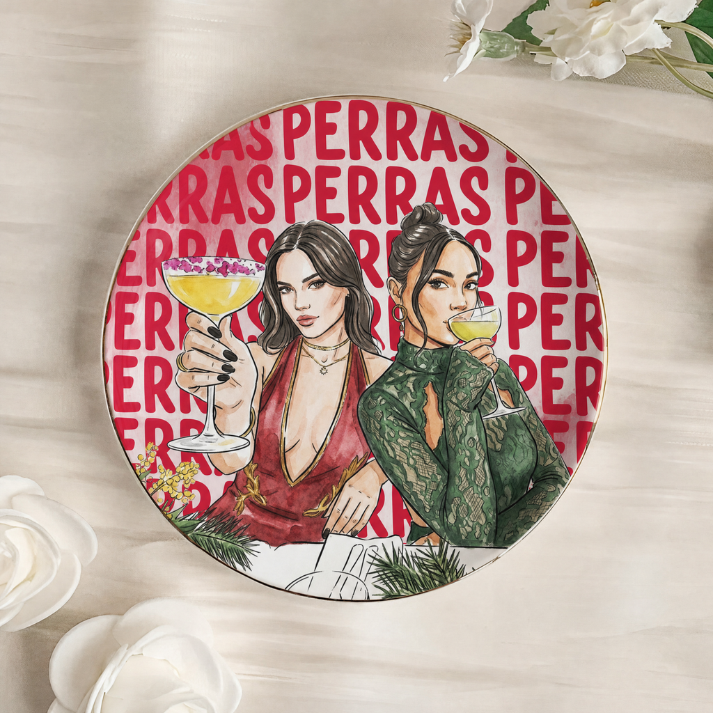 Plato joyero redondo de cerámica con borde dorado, dos amigas brindando ilustradas en acuarela y el título PERRAS repetido de fondo