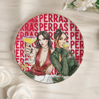 Plato joyero redondo de cerámica con borde dorado, dos amigas brindando ilustradas en acuarela y el título PERRAS repetido de fondo