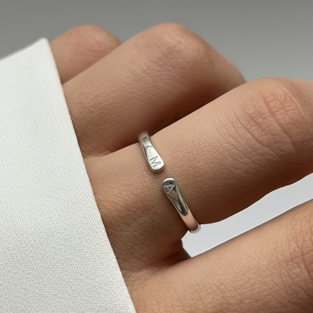 Anillo plateado con dos iniciales grabadas puesto en la mano