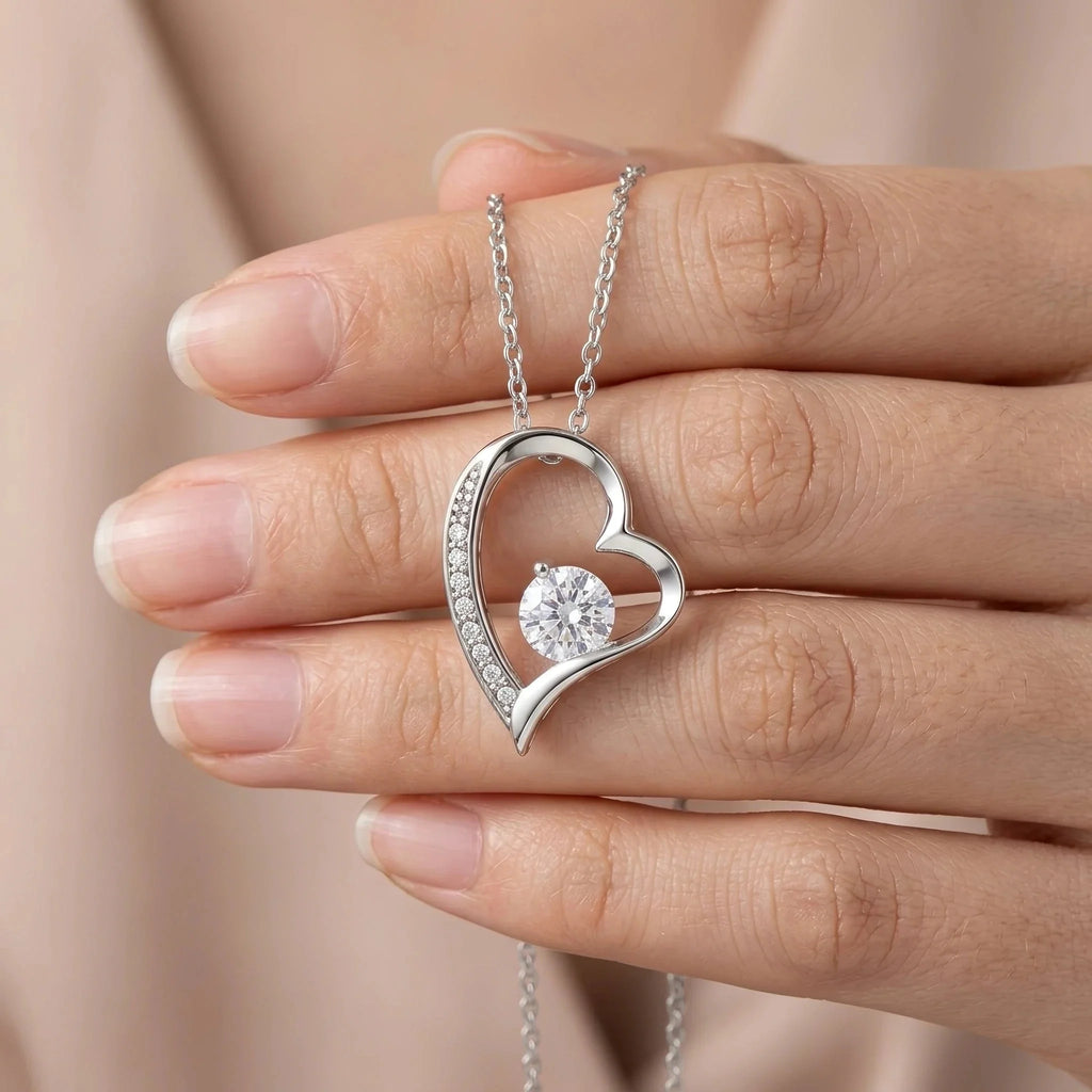 Colgante de corazón con baño de oro blanco en la mano