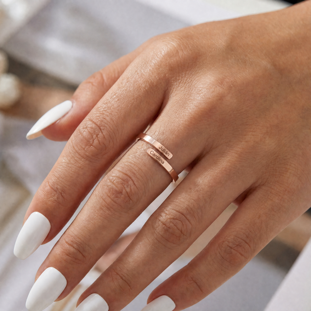 Anillo en oro rosa con los nombres Julián y Carolina, puesto en la mano