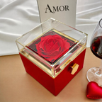 Caja roja con la rosa preservada y la rueda dorada del lateral