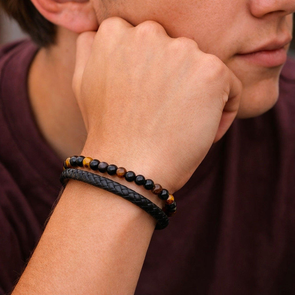 Pulsera de ojo de tigre en la muñeca de un chico joven, con la barbilla apoyada en la mano