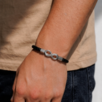 Pulsera de cuero trenzado con el infinito en plata, puesta en la muñeca de un hombre